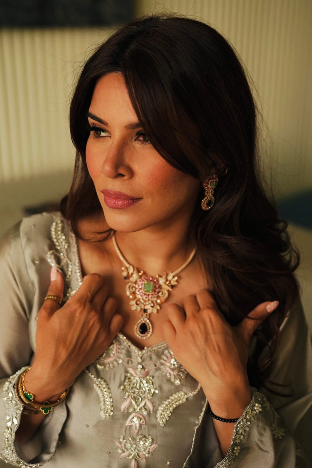 Model wearing Abiha gold plated necklace set with pastel pink and green stones and matching earrings