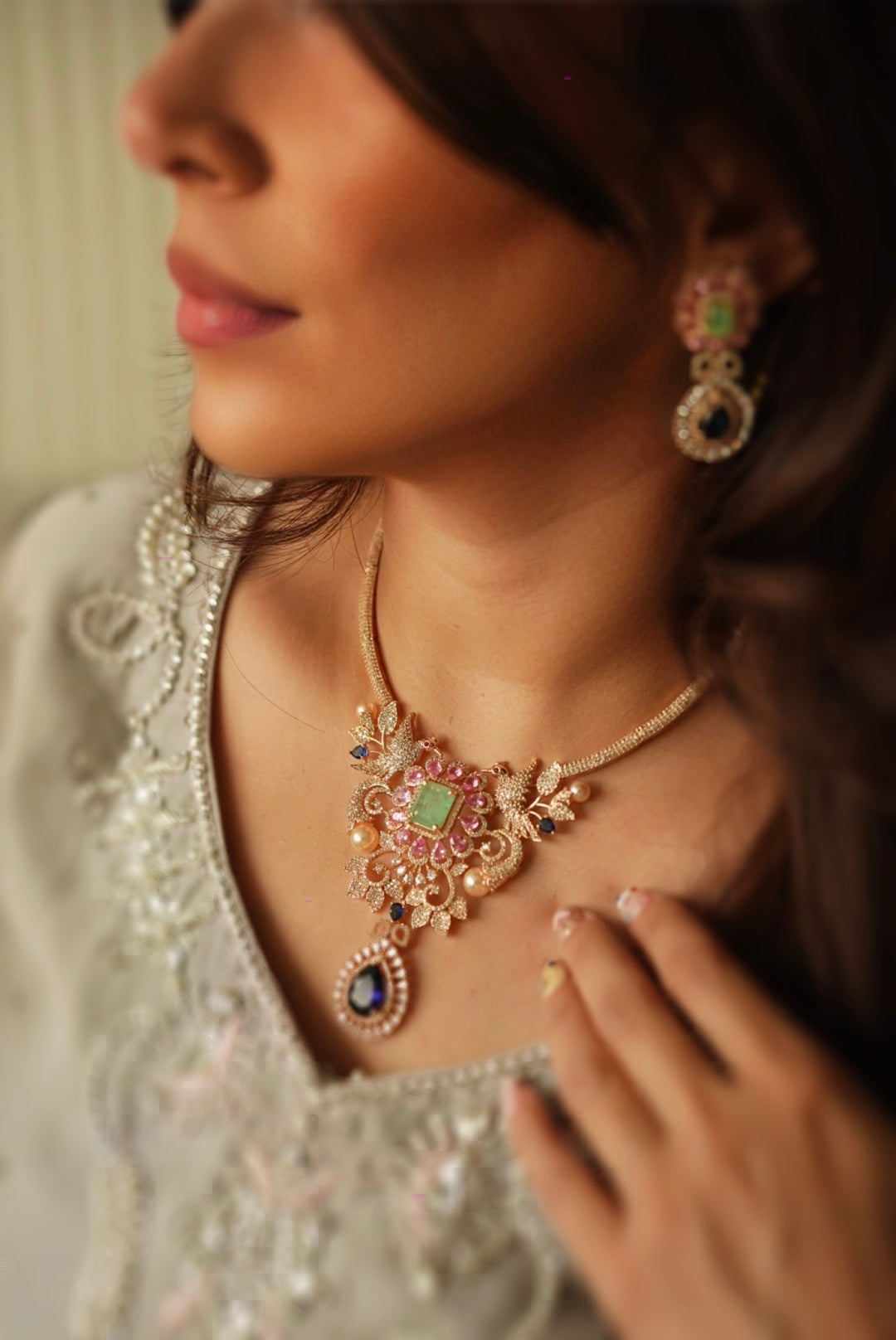 Side view of Abiha crystal necklace set with gold tone detailing and matching drop earrings