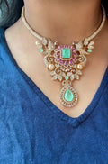 Close-up of gold plated necklace with pastel pink and mint green stones, crystals and teardrop pendant